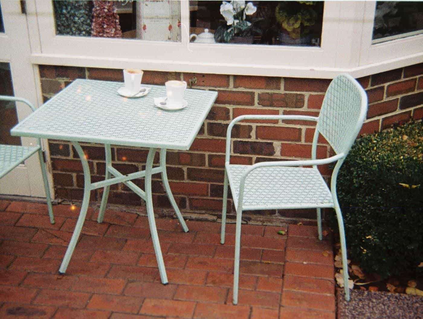 A table with chairs and coffee cups in a garden setting