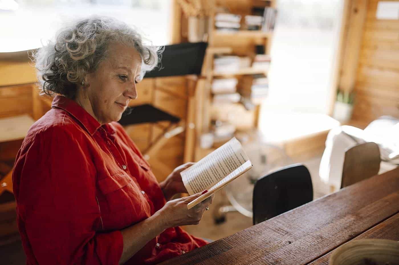 An older woman reading a book indoors