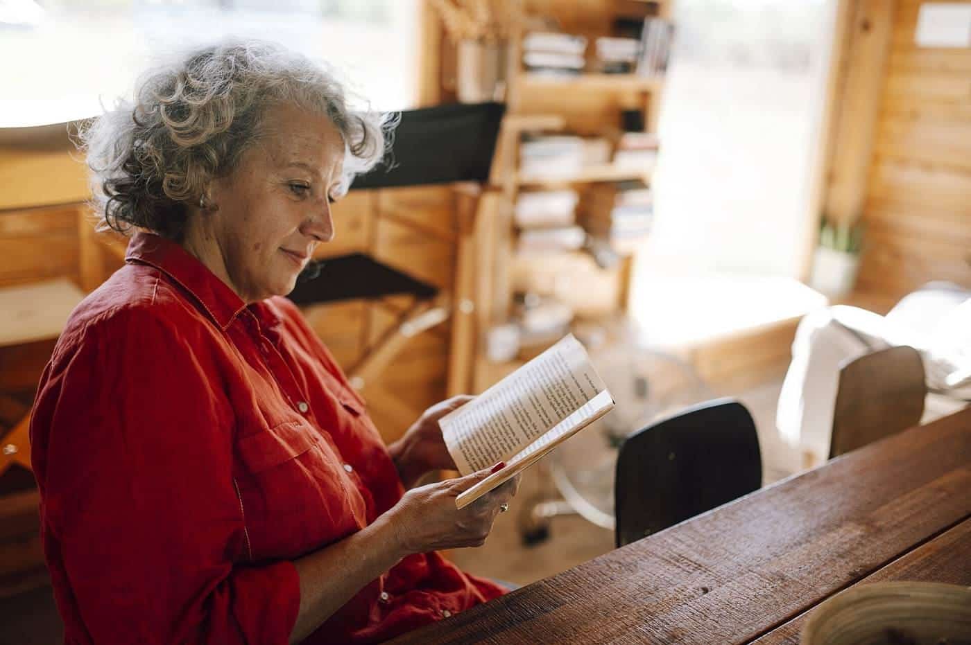An older woman reading a book indoors